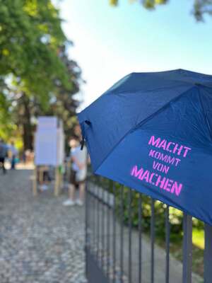 Bunt bespruehter Schirm mit der Aufschrift Macht kommt von machen