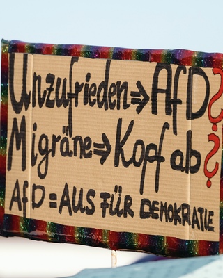Demoschild mit der Aufschrift: Unzufrieden => Afd? Migraene => Kopf ab? Afd= Aus fuer Demokratie